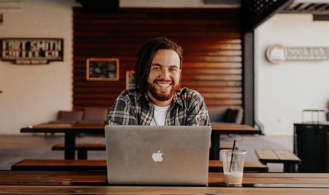 Find your perfect fit at Icon Apartments man sits with a drink in front of an open laptop in local restaurant